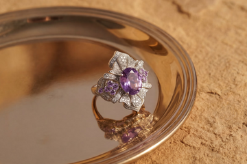 Ring with purple gemstone on a reflective surface