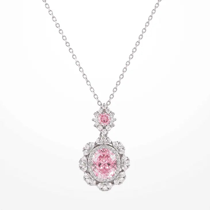 A delicate white gold plated chain necklace featuring a floral pendant with a central oval pink zircon and a smaller round pink zircon above it, set against a plain white background.